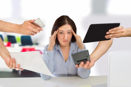 A stressed employee looks overwhelmed at her desk