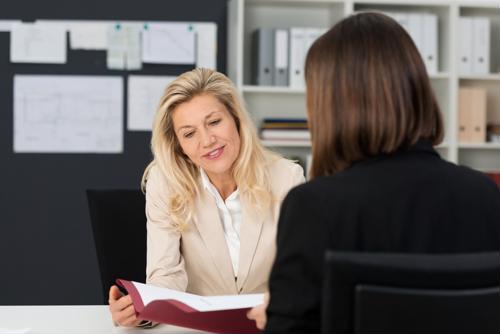 A businesswoman speaks to a woman in an interview setting